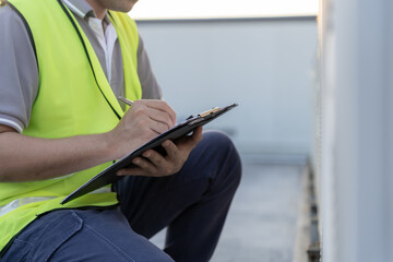 Asian maintenance engineer works on the roof of factory. contractor inspect compressor system and...