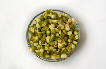 Sprouted moong kept in a glass bowl on a white background with sprouted moong kept in a jar. focus on a Sprouted moong. portrait image.