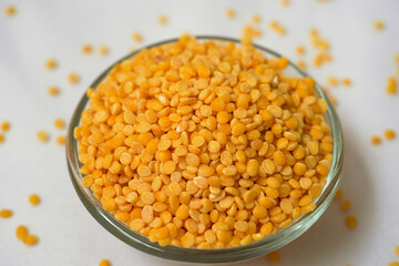 Close up of Organic yellow Gram (Vigna radiata) or split yellow moong dal on a ceramic white bowl with the gradient background of split yellow moong dal. Top view