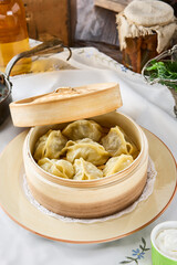 Manty dumplings in bamboo steamer with bright natural light, overhead rustic table composition