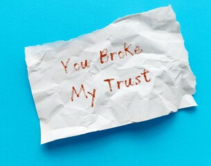 Crumpled paper on blue background written YOU BROKE MY TRUST - means trust is broken when someone...