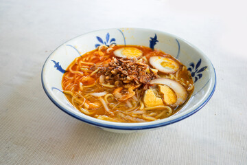 Close up of a bowl of hokkien prawn mee or yellow egg noodles in spicy prawn broth which is popular in Malaysia and Singapore.