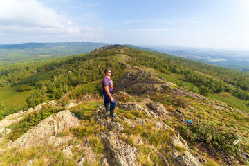Mature tourists on the rocky peak of Yanguzey on the Irendyk ridge in the Southern Urals on a summer day