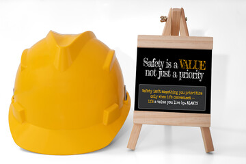 A yellow safety helmet placed beside a chalkboard displaying the safety campaign message : |Safety...