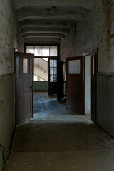 Obraz premium Abandoned industrial hall with old furniture, metal parts, and dusty workspaces. Atmospheric lost place showing decay, machinery remnants, and natural light through large windows.