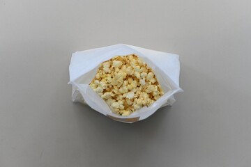 "Top-down shot of butter-flavored popcorn in a white bag on a white background."