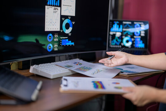 A person is looking at a computer monitor with a lot of graphs and charts on it
