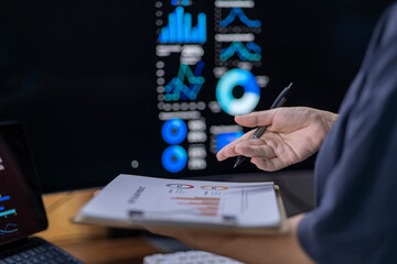 A person is pointing at a computer screen with a pen in their hand