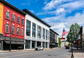 A row of red, white, and gray 19th-century storefronts lines Water Street in Augusta, Maine, United...