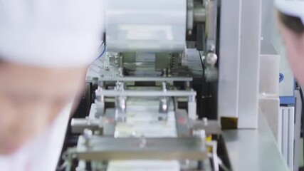 Industrial pharmaceutical workers working at drugs sterile lab packaging factory, pills labeling products on assembly line. Staff wear safety gear, gloves, hats, eye protection, focusing on production