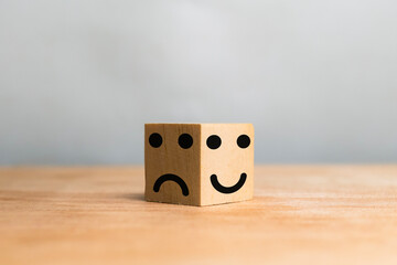 smile expression emoji on bright side and bad expression on dark side on wooden cube on the table