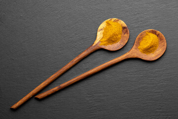 Wooden Spoons with Turmeric Powder on Slate Background – Natural Cooking Ingredients