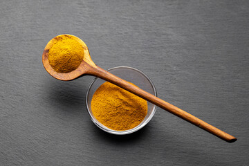Wooden Spoons with Turmeric Powder on Slate Background – Natural Cooking Ingredients