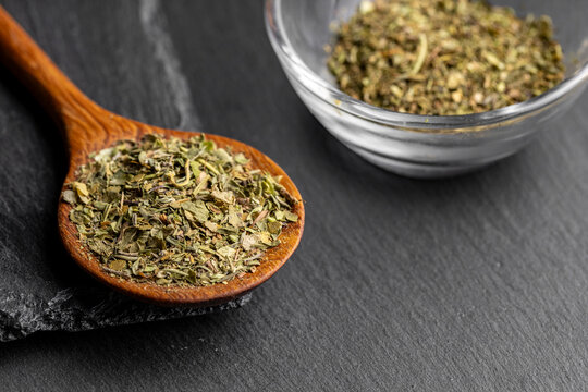 Wooden spoon with mixed dried fine herbs on a dark slate background