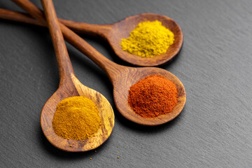 Colorful Spices on Wooden Spoons – Curry, Turmeric, and Paprika on Dark Slate Background
