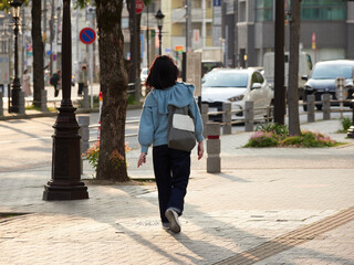 午後の都市の街で歩く一人の若い女性の姿
