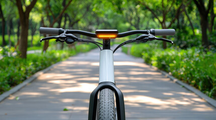 Electric bicycle handlebar, dashboard, and front wheel on park pathway, surrounded by green trees, modern and eco friendly