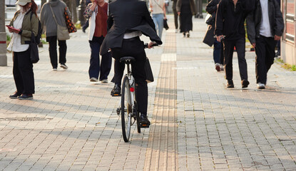 日本の都市の街の通行人と自転車を乗るサラリーマンの姿