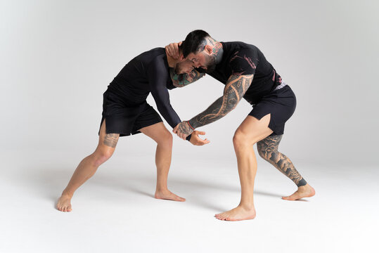 Two male wrestlers grappling in studio on white background