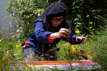 Female artist dripping paint onto canvas in a garden