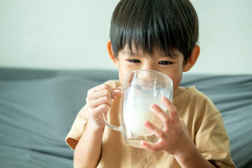 Asian boy is drinking a glass of milk.