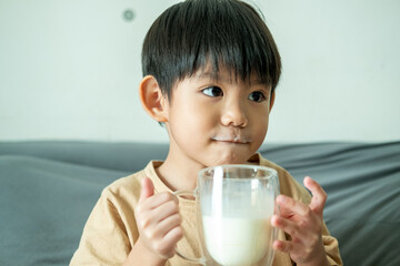 Asian boy is drinking a glass of milk.