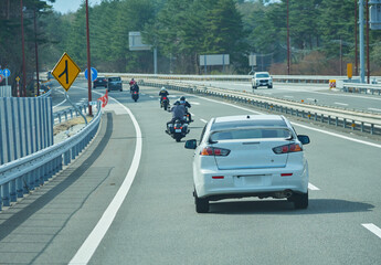 高速道路で走る車とオートバイの集団