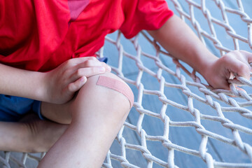Asian boy sitting on a net with wound dressing plaster.