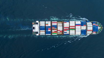 Aerial view of a cargo container ship sailing across the open sea, stacked high with colorful...