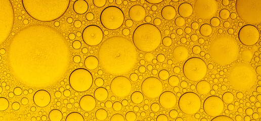 Macro abstract image of golden oil bubbles suspended in liquid, forming overlapping circular...