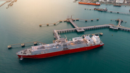 Aerial view of an LNG tanker docked at an offshore terminal with multiple pipelines, storage tanks,...