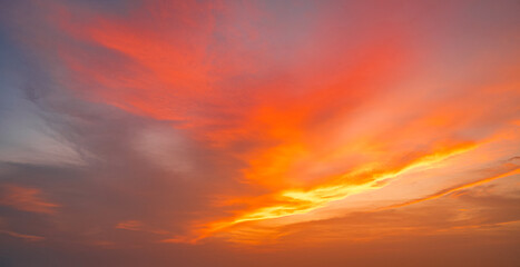 Vibrant fiery sunset over the ocean with silhouettes of cargo ships on the horizon, painting the...
