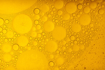 Macro abstract image of golden oil bubbles suspended in liquid, forming overlapping circular...