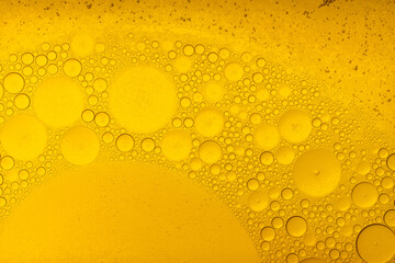 Macro abstract image of golden oil bubbles suspended in liquid, forming overlapping circular...