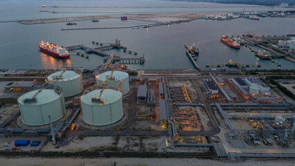 Aerial view of an LNG tanker docked at an offshore terminal with multiple pipelines, storage tanks,...