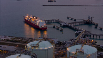 Aerial view of an LNG tanker docked at an offshore terminal with multiple pipelines, storage tanks,...