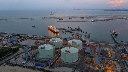 Aerial view of an LNG tanker docked at an offshore terminal with multiple pipelines, storage tanks,...