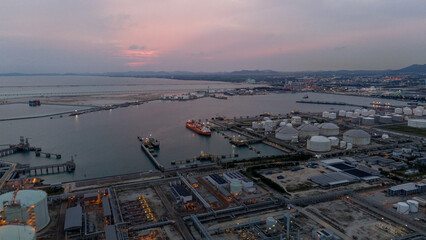 large oil tanker docked at a refinery terminal with multiple white storage tanks, complex pipeline...
