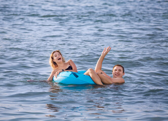 A cheerful young couple swims in the sea with an inflatable circle