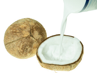 Fresh coconut milk being poured into a halved coconut shell, isolated on white background. Concept of tropical cuisine, plant-based milk, and organic food ingredients.