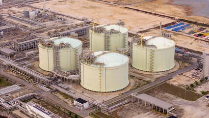 LNG storage tanks and terminal facility at dusk, showcasing large cylindrical containers, offshore piers, and cargo ships. Industrial landscape representing global liquefied natural gas