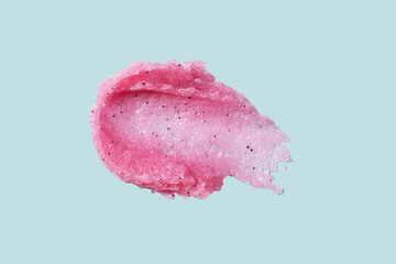 Smear texture of pink raspberry scrub on blue background. Fruit exfoliation scrubber for body and face in SPA. Body care scrub for design.