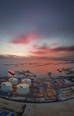 Aerial view of an LNG tanker docked at an offshore terminal with multiple pipelines, storage tanks, and an industrial complex. Captures global energy logistics