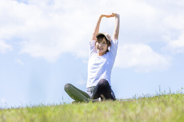 緑の丘でストレッチする女性	
