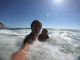 Sea waves splashing on happy couple.