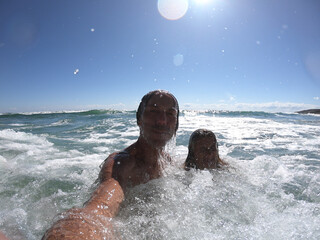 Sea waves splashing on happy couple.
