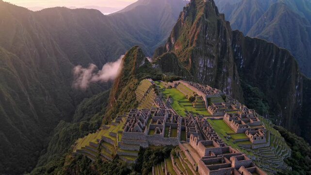 Aerial view of Machu Picchu at sunrise, showcasing ancient ruins and lush mountains. Perfect for a travel video highlighting historic sites.