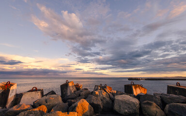 Sunset light warms the rugged sea defenses at Ballina in New South Wales, Australia where dramatic...