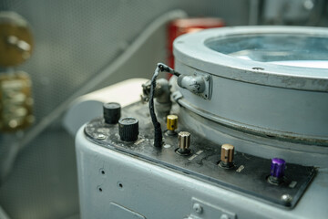 A close-up view of a control panel on a ship shows several colored metal switches and knobs. The...