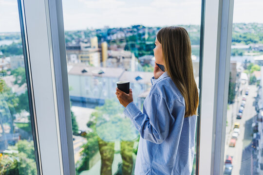 A contemplative woman is savoring a cup of coffee while taking in a breathtaking scenic view of the city skyline from her chic modern apartment. This moment encapsulates balance and mindfulness - Powered by Adobe